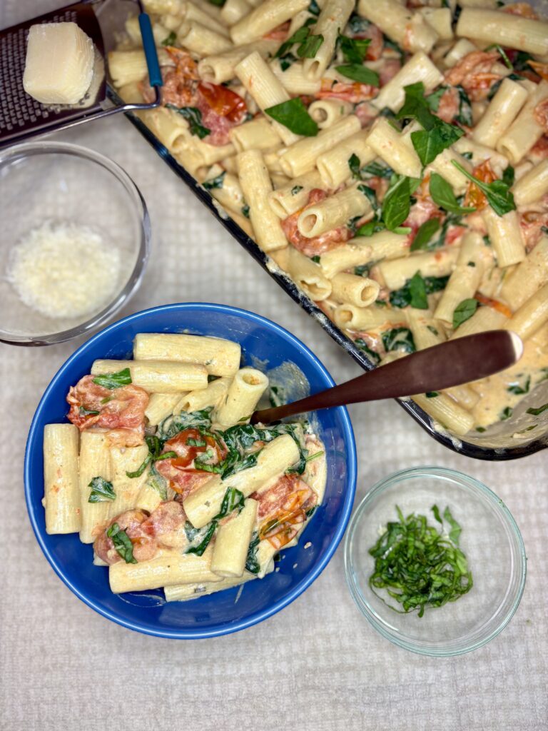 Baked Boursin Pasta in a bowl next to a baking dish on a counter