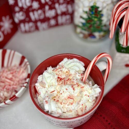 a mug of Peppermint cocoa cocktail on a counter next to bowls of toppings