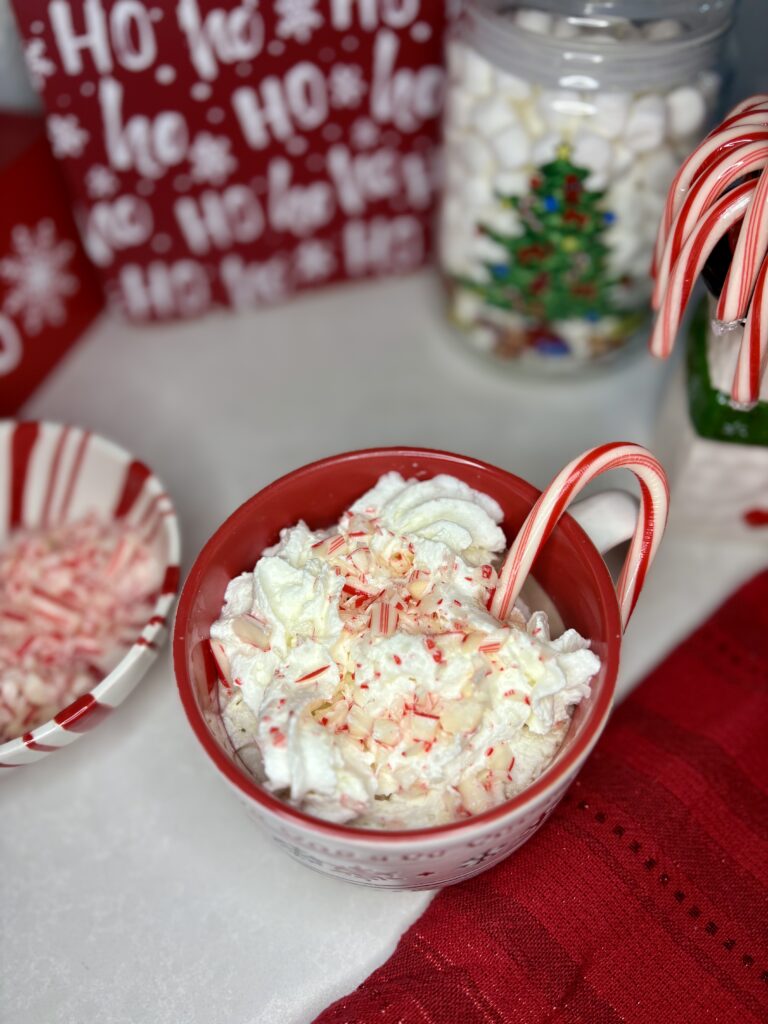 a mug of Peppermint cocoa cocktail on a counter next to bowls of toppings