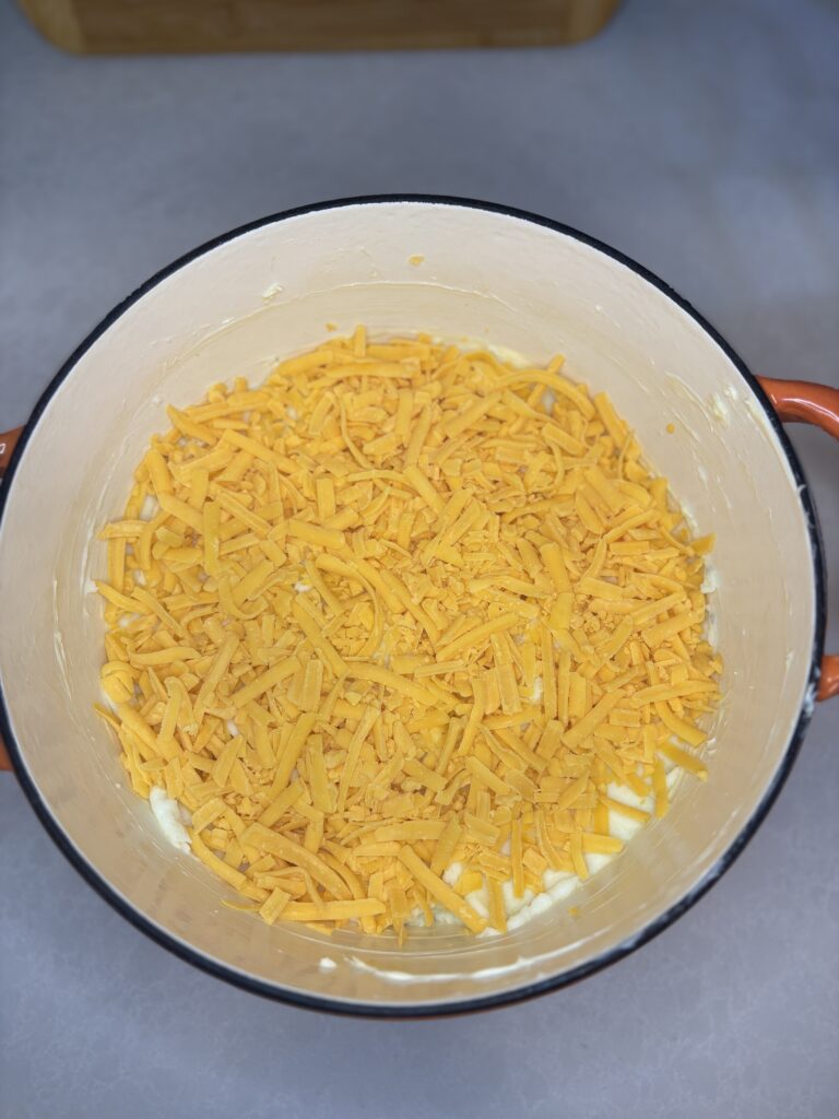 mashed potatoes in a baking dish with shredded cheese