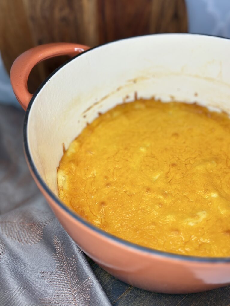 a pot with cooked cheesy holiday potatoes on a counter