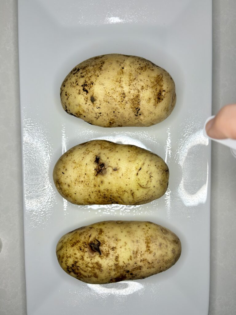 olive oil being sprayed onto potatoes on a plate