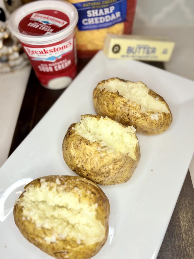 cooked potatoes on a plate next to sour cream, butter, and cheese