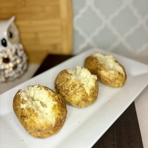 3 cooked baked potatoes on a plate on a counter