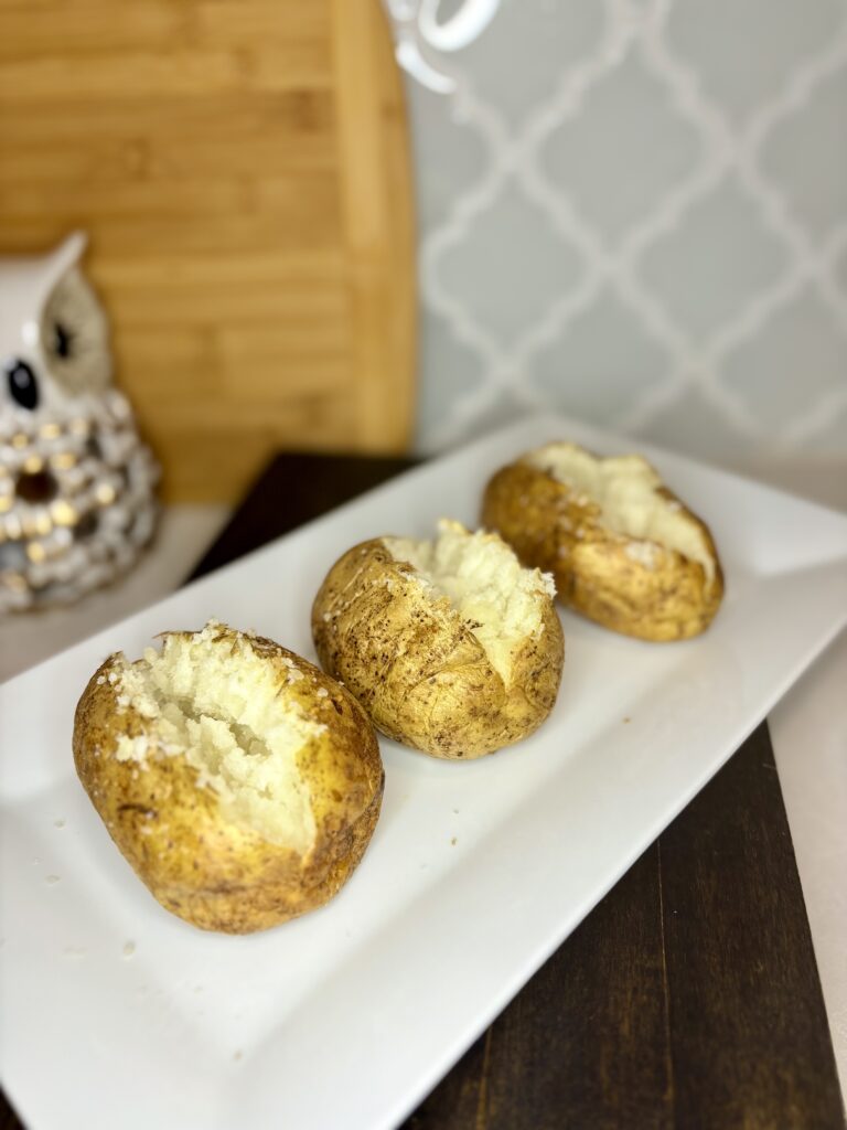 3 cooked baked potatoes on a plate on a counter