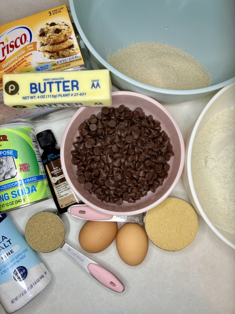 chocolate chips, sugars, flour, salt, baking soda, vanilla extract, butter, crisco and eggs on a counter