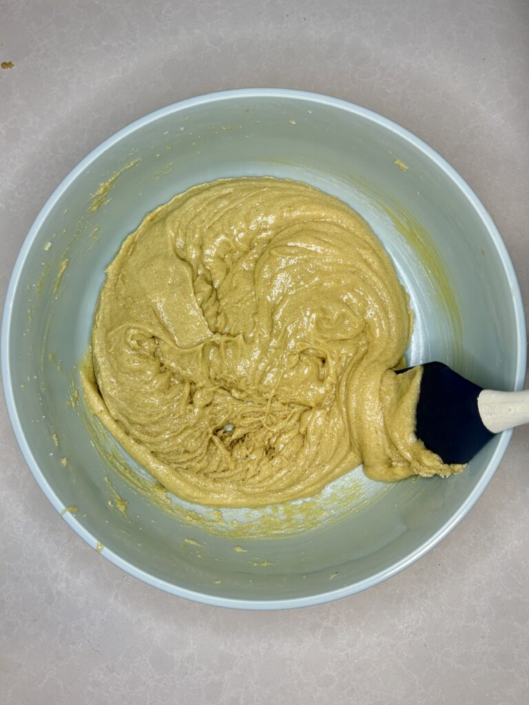 a spatula scraping the dough from the sides of the bowl