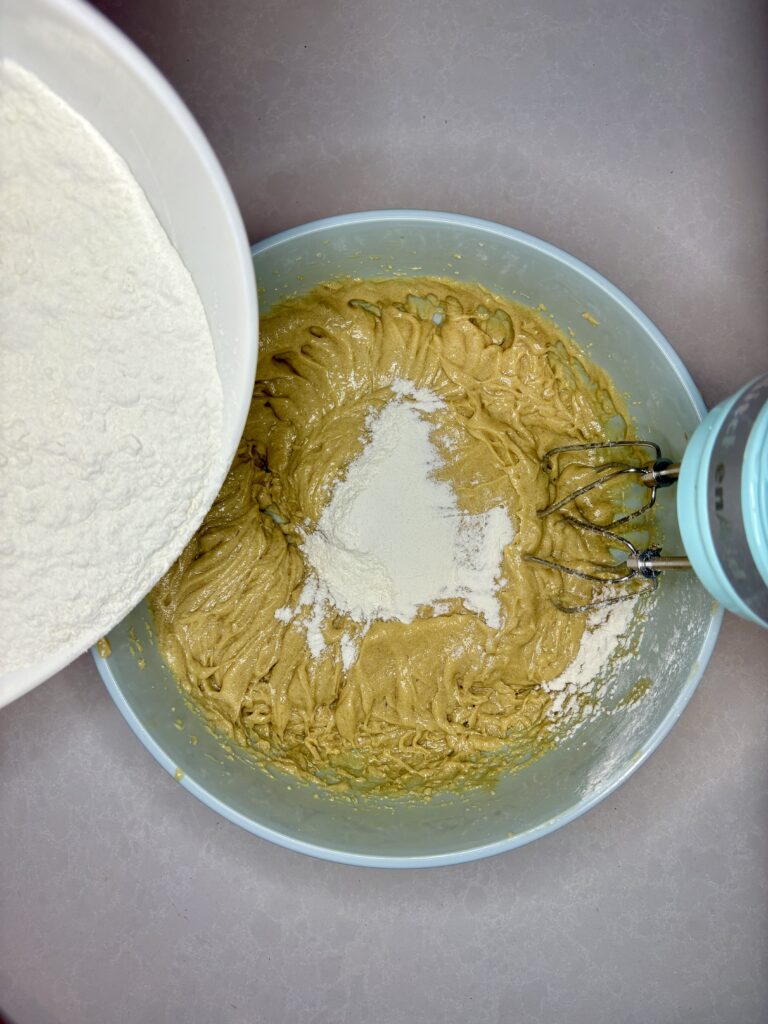 flour being added to the dough in a bowl