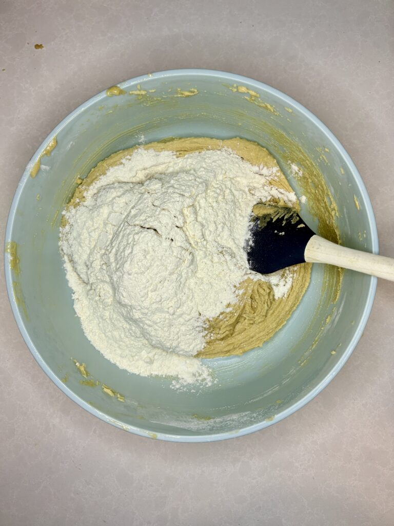 a spatula stirring flour into dough in bowl