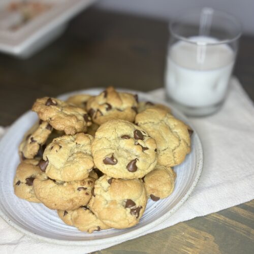 chocolate chip cookies on a plate next to a glass of milk on a table