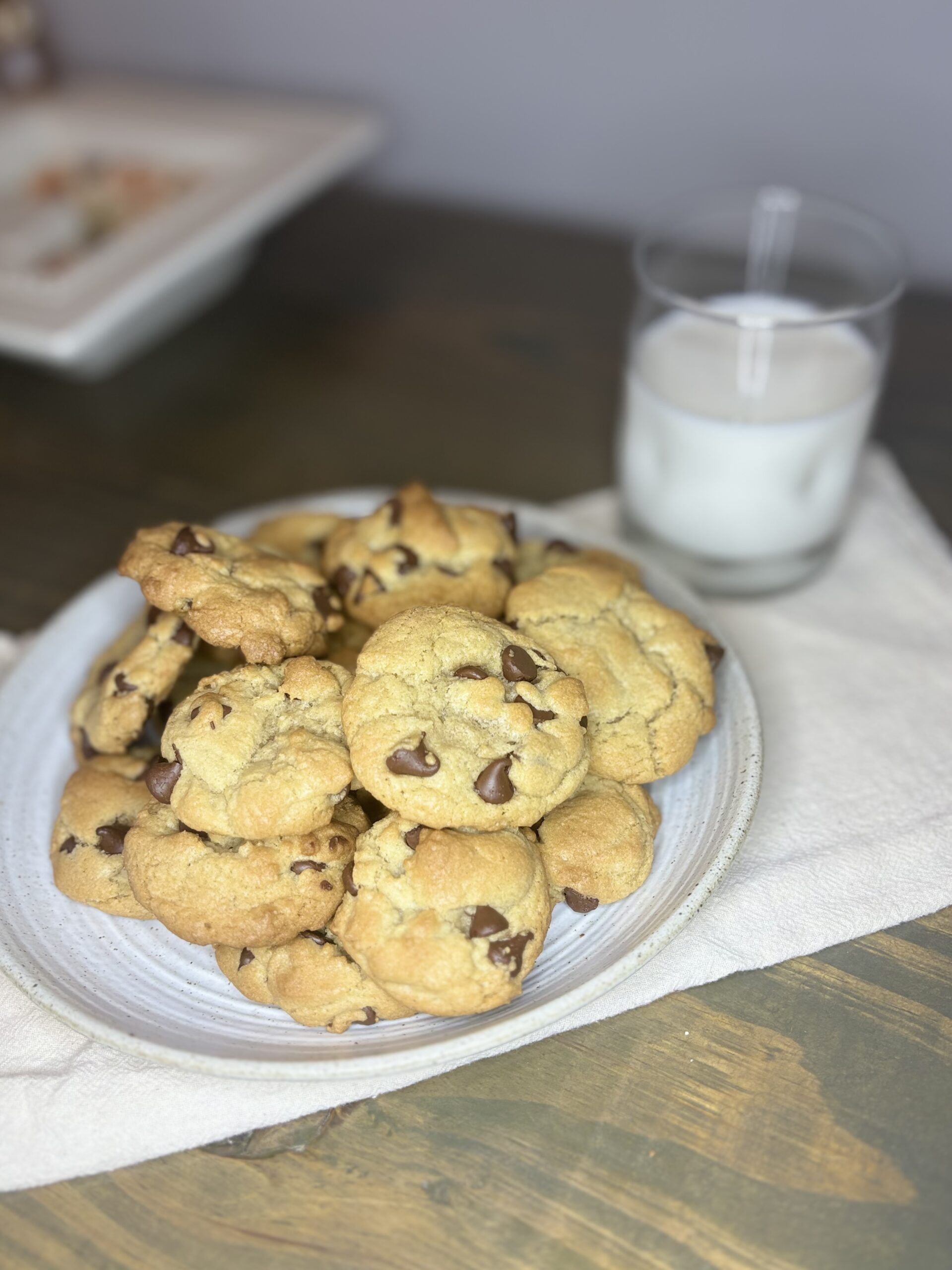 chocolate chip cookies on a plate next to a glass of milk on a table