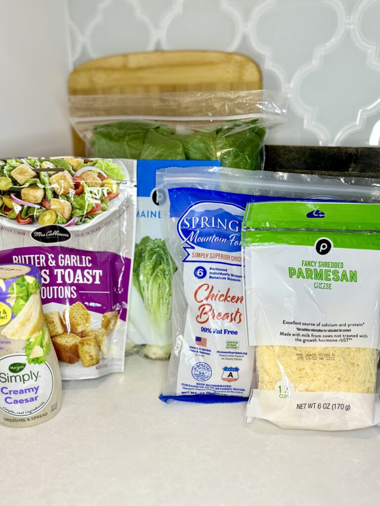 chicken breasts, lettuce, cheese, dressing and croutons on a counter