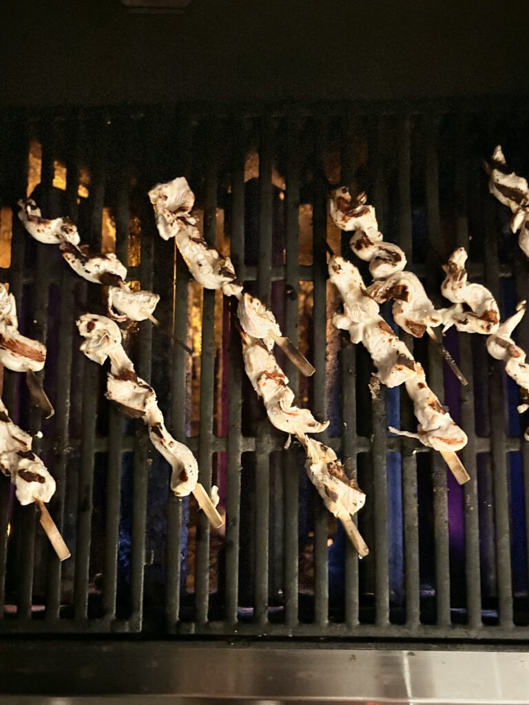 chicken skewers cooking on a grill