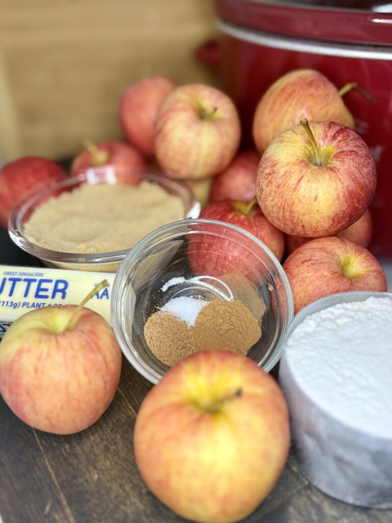 apples on a cutting board with flour, butter and seasoning in a bowl