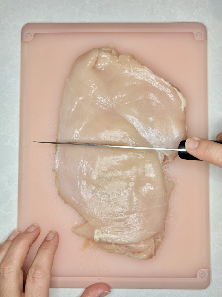 a flattened chicken breast being sliced in two