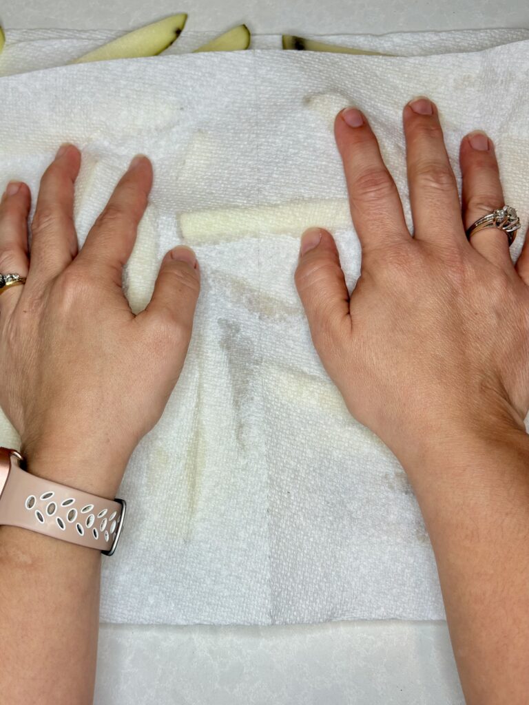 hands using paper towels to dry potatoes