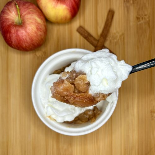 cinnamon streusel apples in a bowl topped with whipped cream