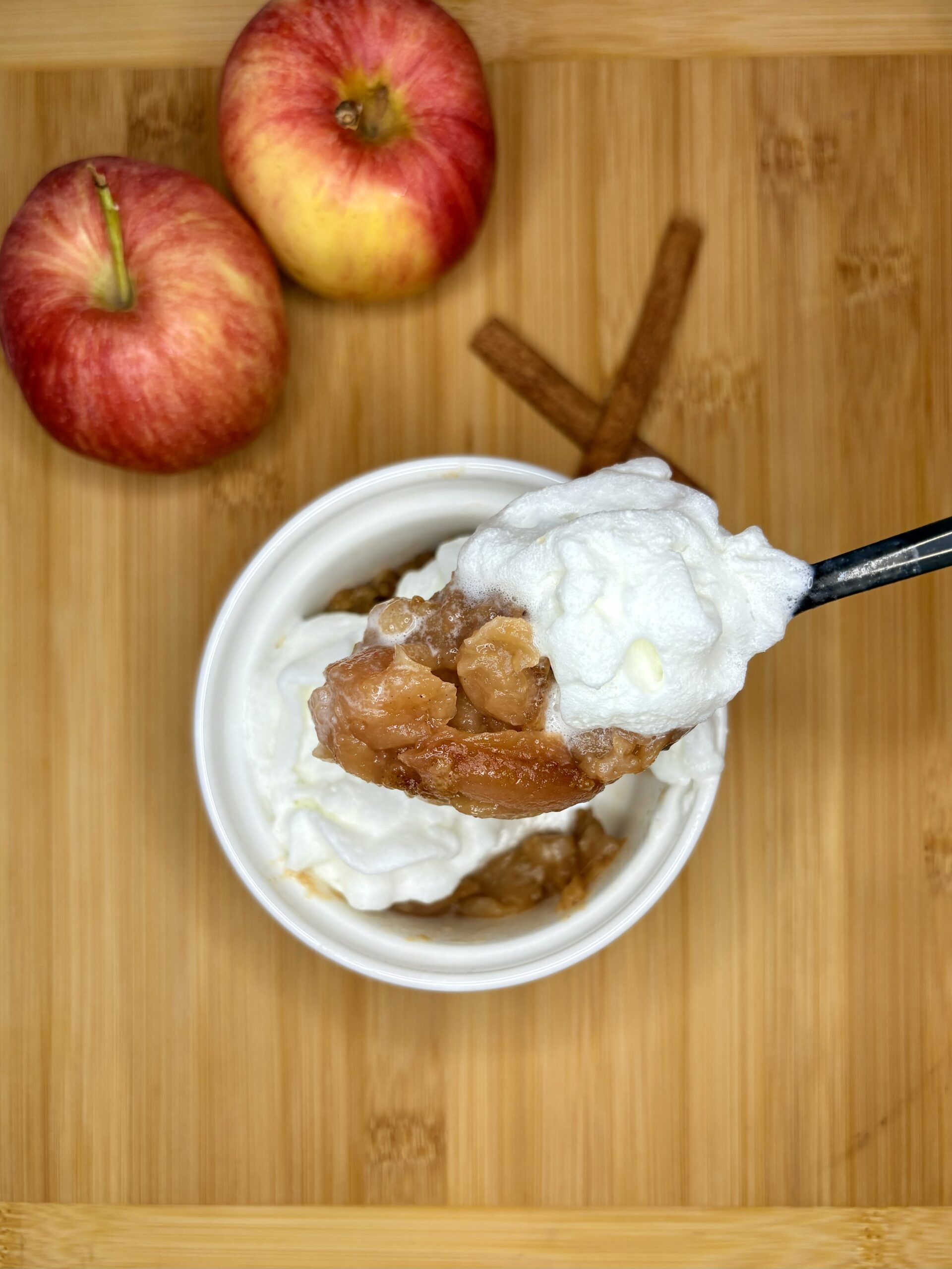 cinnamon streusel apples in a bowl topped with whipped cream