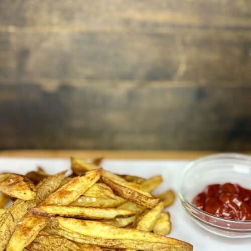 oven fries on a plate next to ketchup