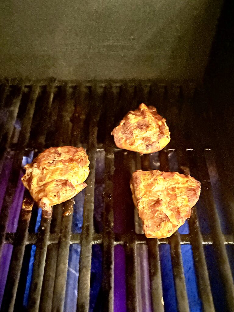 cooked chicken on a grill topped with buffalo sauce