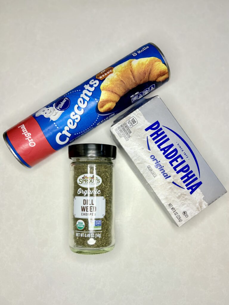 a package of refrigerated crescent dough, dill seasoning, and a block of cream cheese on a counter