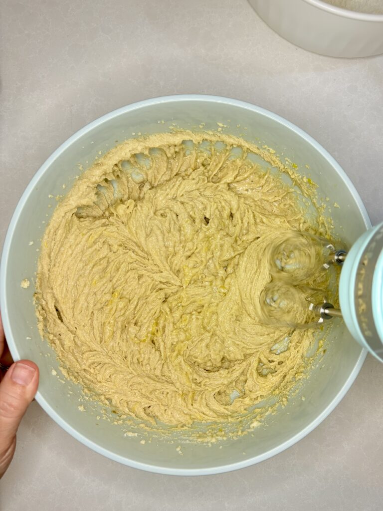 a hand mixer beating the butters and sugars together