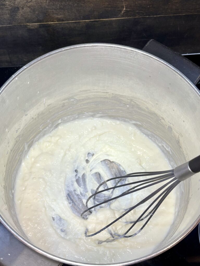 milk being whisked into flour and butter