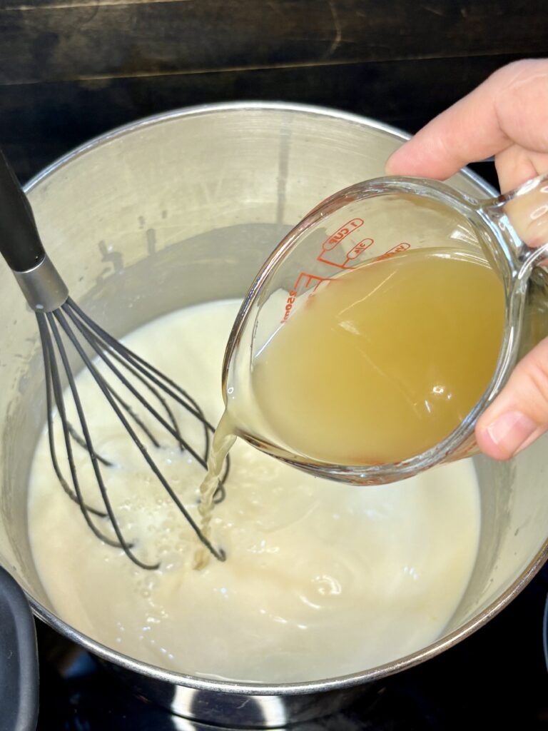 chicken being poured into pot with milk, flour and butter