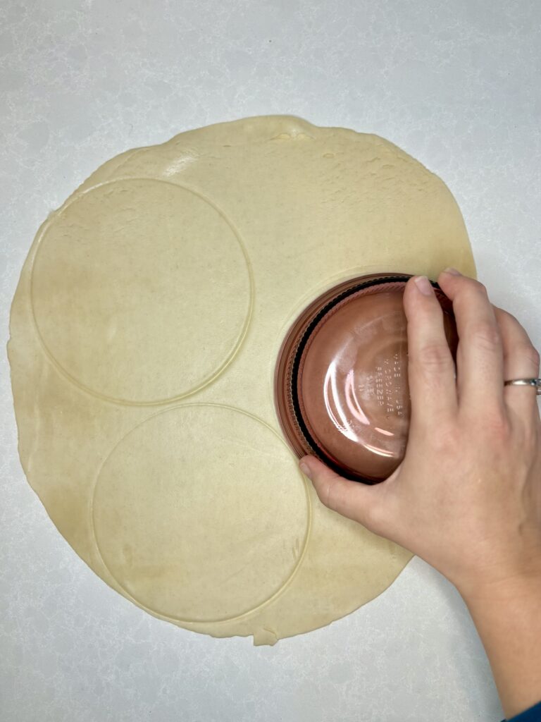 circles being cut out of pie crust using a round dish