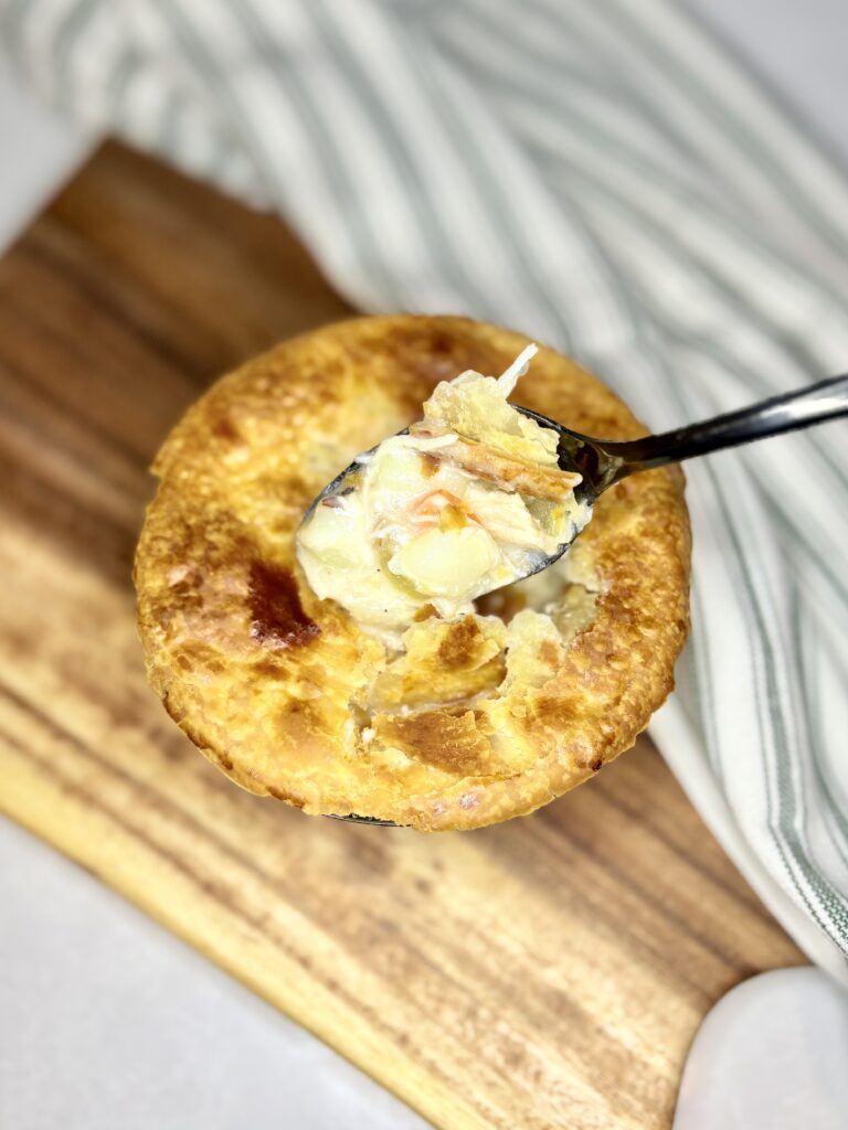 chicken pot pie in an individual baking dish on a board on a counter next to a towel