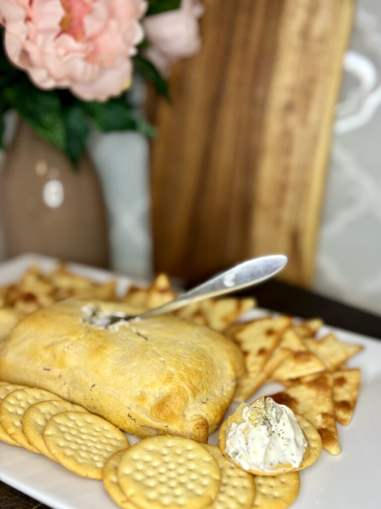 creamy dill dip on a plate with crackers on a counter