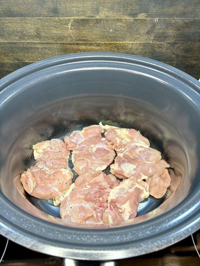 chicken thighs being browned in a pot on a stove