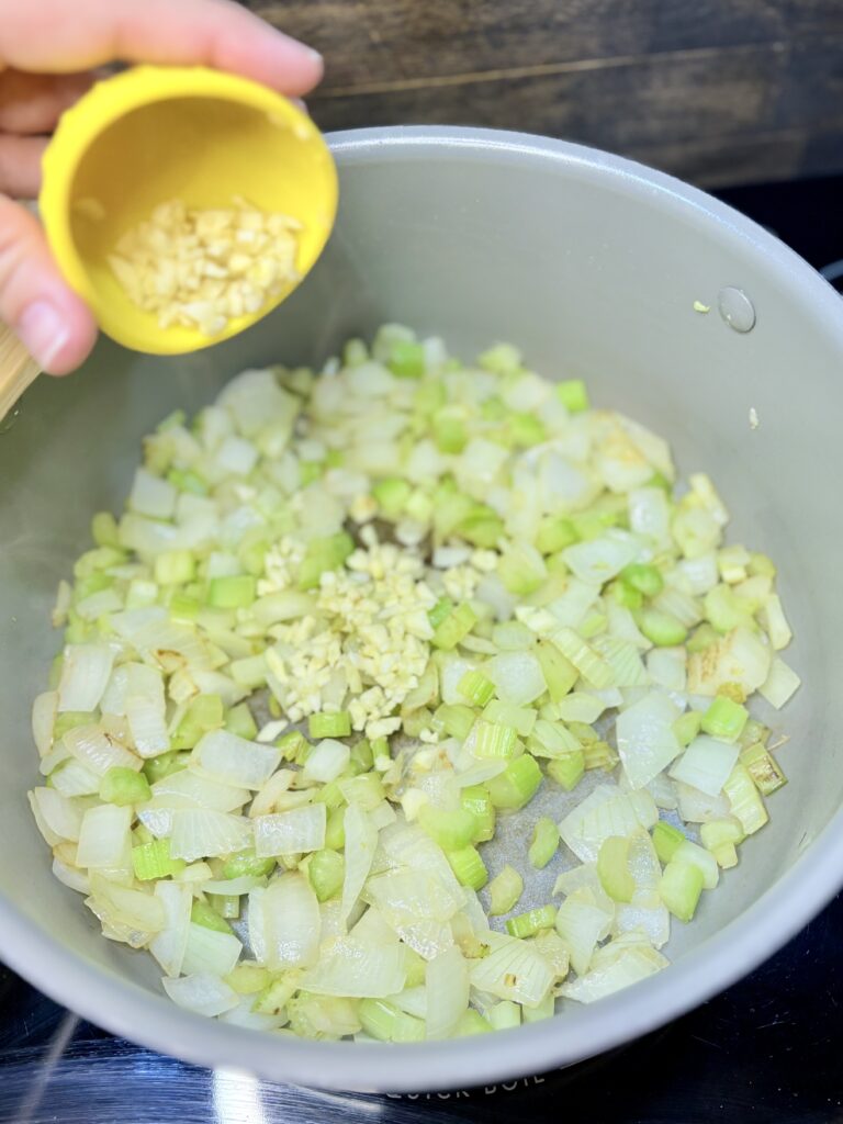 garlic being added to celery and onion