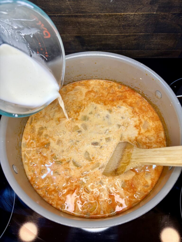 half and half being stirred in to pot of soup