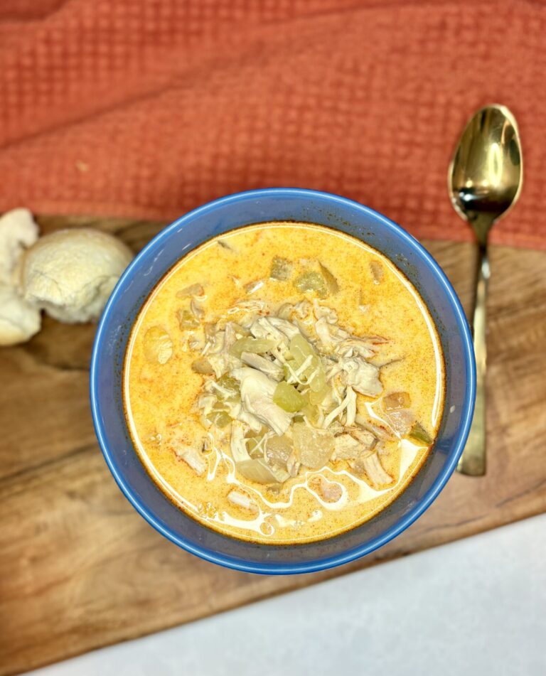 buffalo chicken soup in a bowl next to bread and a spoon on a counter