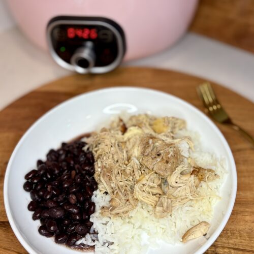 cooked mojo chicken over rice next to black beans on a plate