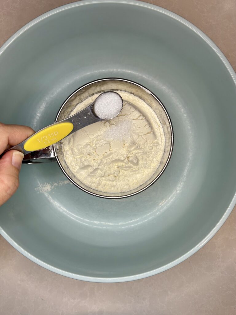 a bowl with a sifter inside and flour and salt inside sifter