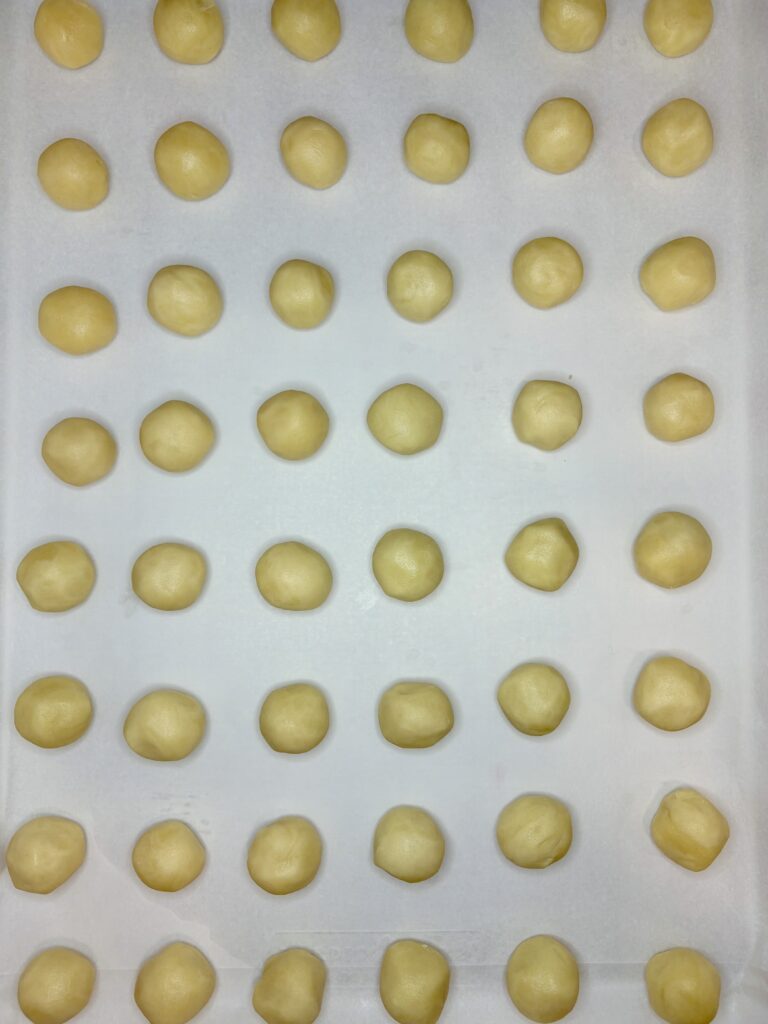 a baking sheet lined with parchment paper and rows of cookie dough