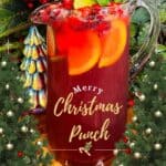 Festive Christmas punch with citrus slices, berries, and mint in a glass pitcher, surrounded by holiday decorations and greenery, perfect for holiday gatherings and seasonal celebrations.