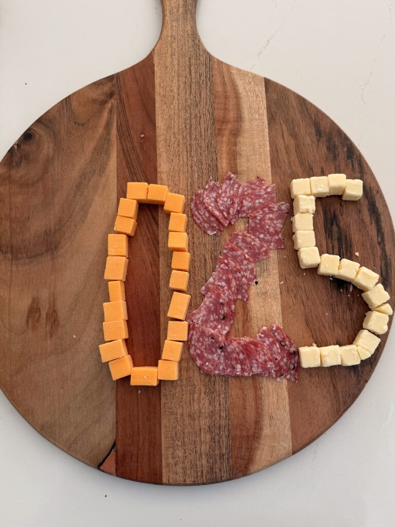 Cubed cheeses making the shape of the number 025 on the large brown board on the counter.