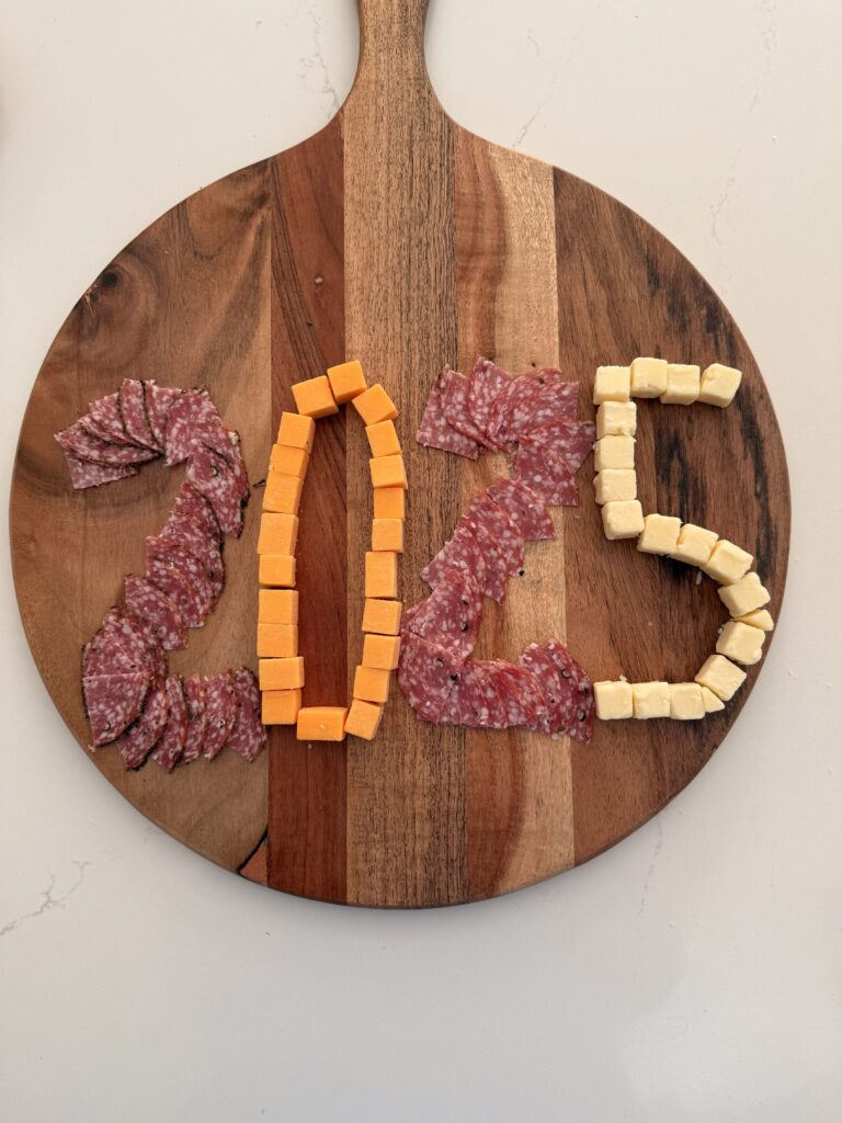 Cubed cheeses making the shape of the number 2025 on the large brown board on the counter.