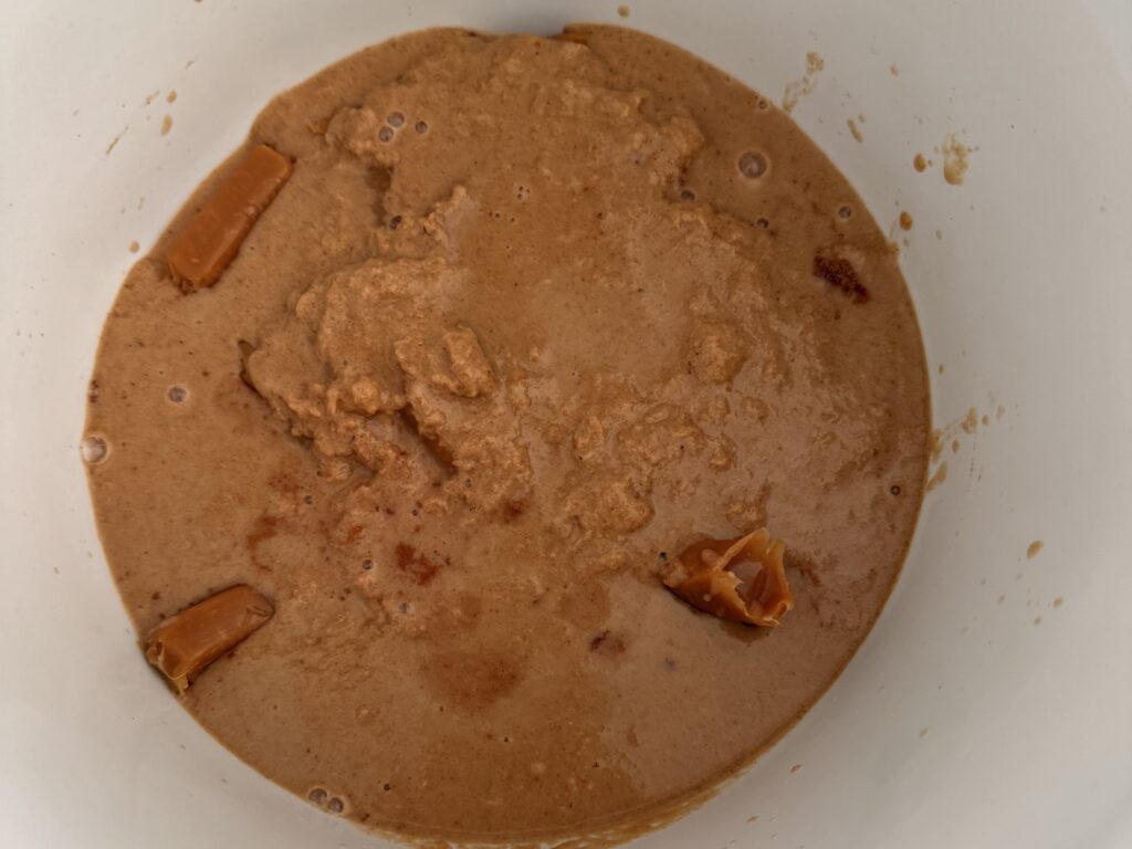 apple juice, vanilla, cardamon, cinnamon and peanut butter mixture in the slow cooker with the unwrapped caramels on the counter.