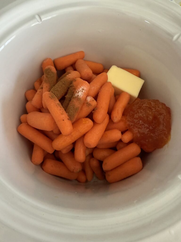 baby carrots, butter, salt, apricot jam, cinnamon and water in the slow cooker on the counter.