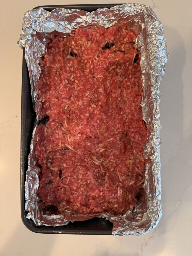 molded meatloaf in a foil lined loaf Tim on the counter.