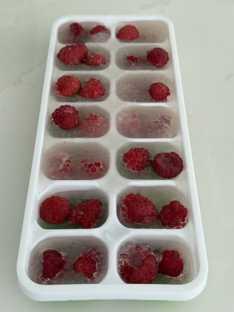 fresh raspberries and juice mixture in an ice cube tray on the counter.