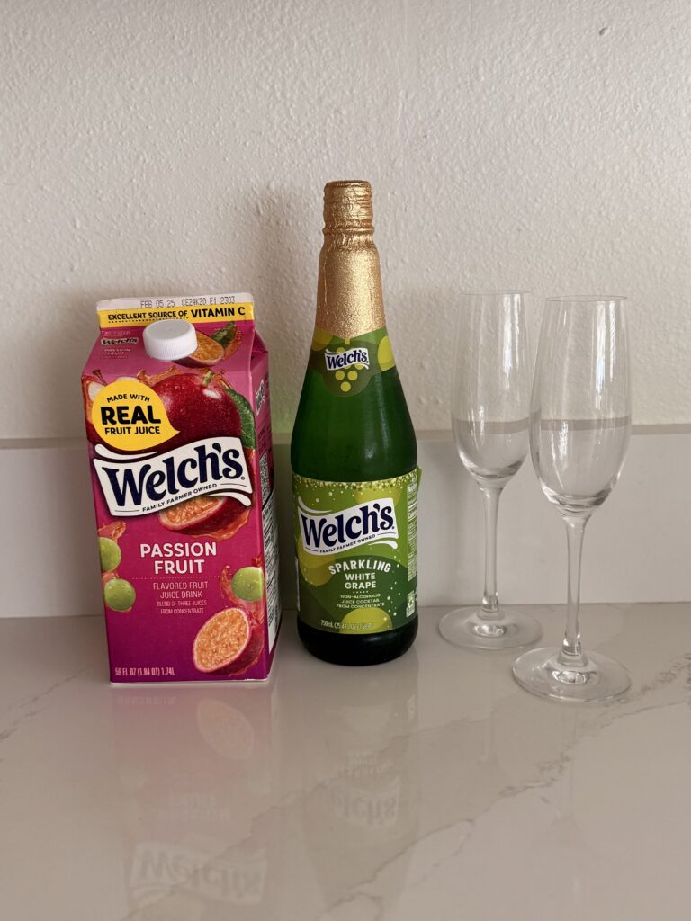 passion fruit juice and sparkling white grape juice on the counter with two champagne flutes.