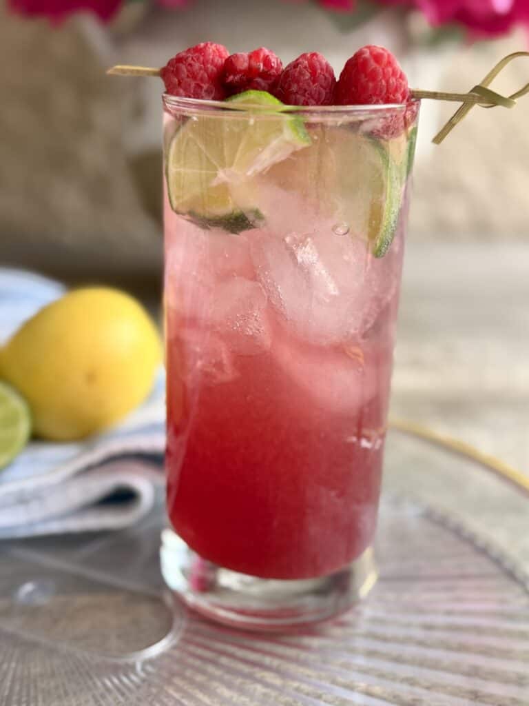 Cran-Raspberry LIme Rickey on a glass tray on a brown outside table.