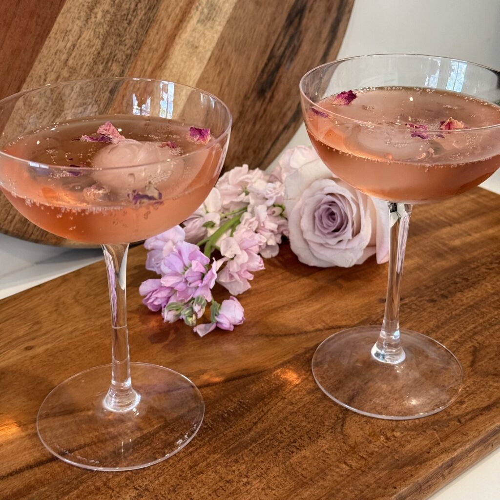 2 glassed of The Rosette cocktail on a cutting board on the counter.