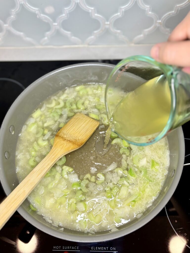 broth being poured into a pan with celery and onion