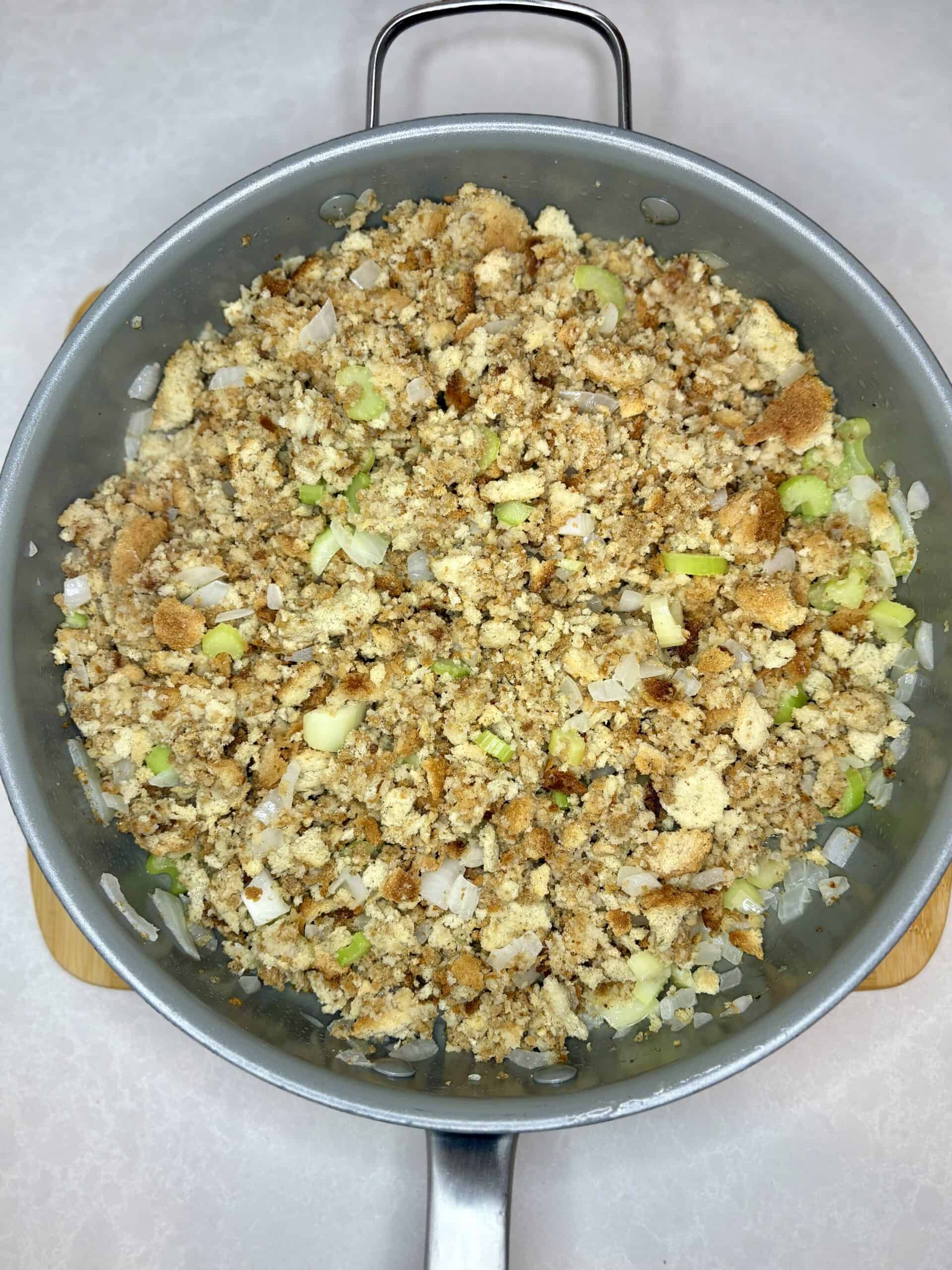Crumbled biscuit topping with chopped green onions in a skillet.